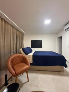 a bedroom with a bed and a chair and a tv at Duplex Coité in Conceição do Coité