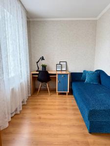 a living room with a blue couch and a desk at Center two bedroom apartment in Daugavpils