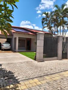a house with a gate and palm trees at Quarto em Foz, ótima localização em casa familiar in Foz do Iguaçu