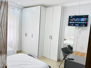 a bedroom with white cabinets and a flat screen tv at Pwake Luna Guesthouse in Swakopmund