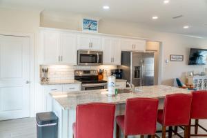 a kitchen with white cabinets and red chairs at Sunset Blessing - 207 Arias Ct in Dauphin Island