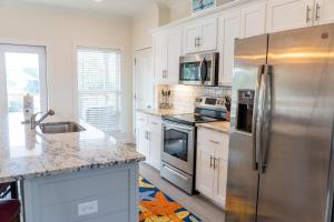 a kitchen with white cabinets and stainless steel appliances at Sunset Blessing - 207 Arias Ct in Dauphin Island