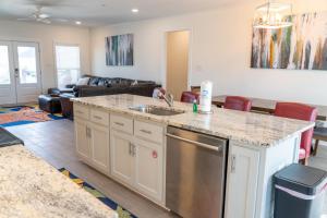 a kitchen with a sink and a living room at Sunset Blessing - 207 Arias Ct in Dauphin Island +29 photos