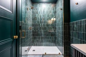 a bathroom with a shower with green tiles at Hollyhock Suite 411 in Louisville