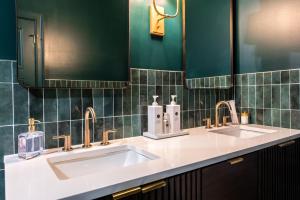 a bathroom with two sinks and green tiled walls at Hollyhock Suite 411 in Louisville