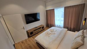 a bedroom with a white bed and a flat screen tv at Apartment Local Uetendorf in Uetendorf