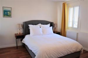 a bedroom with a bed with white sheets and a window at La suite dorée in Étretat
