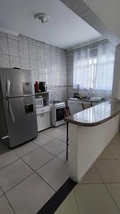 a kitchen with a refrigerator and a counter in it at Quarto Prime até 4 pessoas familia, piscina, Pousada Lua Encantada Pousada Tijucas in Tijucas