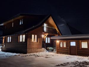 a wooden house in the snow at night at Drevenica Skye Terchová in Terchová
