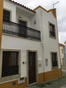 a white building with a balcony and a door at Maresia in Sines