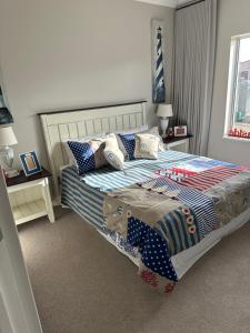 a bedroom with a large bed with blue and white sheets at Sea Breeze in Mossel Bay