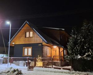 a wooden house in the snow at night at Drevenica Skye Terchová in Terchová