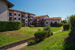 eine Reihe von Häusern in einem grünen Hof mit einem Gebäude in der Unterkunft La Casa Di Miele in Marcignago