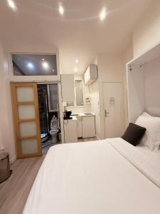 a bedroom with a large white bed and a bathroom at Rempart du Chateau-SV85 StudioVincennes in Vincennes