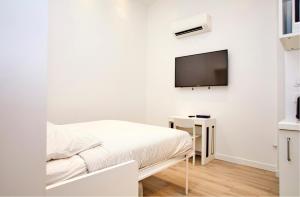 a white room with a bed and a tv on the wall at Rempart du Chateau-SV85 StudioVincennes in Vincennes