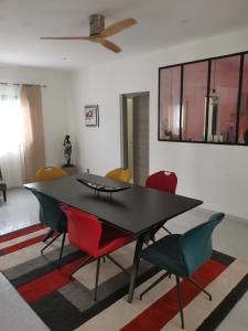 a dining room with a black table and red chairs at VILLA Keur Diam in Somone