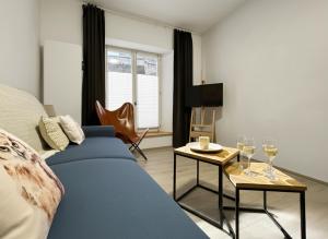 a living room with a blue couch and a table with wine glasses at le Gîte du Hibou in Rodemack