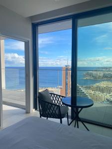 a bedroom with a table and a view of the ocean at Mercury tower Elena K 24th Floor panoramic view Apt in St. Julianʼs