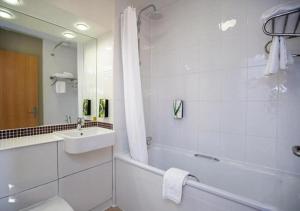 a white bathroom with a tub and a sink at ALTY Hotel in Broadheath +13 photos