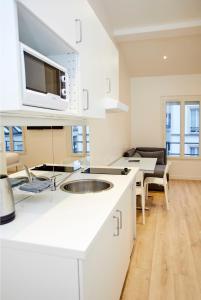 a white kitchen with a sink and a microwave at Rempart du Chateau-SV86 StudioVincennes in Vincennes