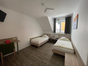 a room with two beds and a desk and a window at Hotel & Restaurant Friedrichshöhe in Braunschweig