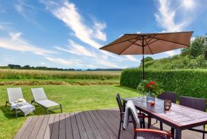 a wooden deck with a table and an umbrella at Ferienhaus Backsteinquartier D in Putbus mit Sauna und Kamin in Putbus