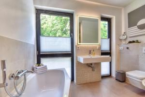 a bathroom with a tub and a sink and a toilet at Ferienhaus Backsteinquartier D in Putbus mit Sauna und Kamin in Putbus +10 photos