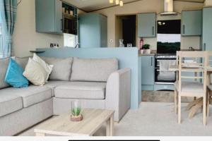 a living room with a couch and a kitchen at Luxury caravan-Sleeps 6- Pets Ok-Site Pool in Hunstanton