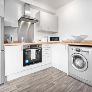 a kitchen with white cabinets and a washer and dryer at Modern 2 Bed Apartment - Parking - Smart TV - Fast Wi-Fi 27CR in Sleightholme