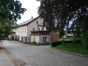 a large white house on a cobblestone street at Ferienwohnung Pferdestall in Reinhardtsdorf