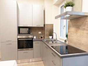 a kitchen with white cabinets and a sink at Quick Home - Edera in Biella +1 photo