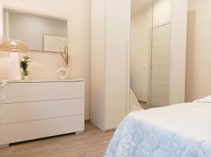 a white bedroom with a dresser and a mirror at Quick Home - Edera in Biella