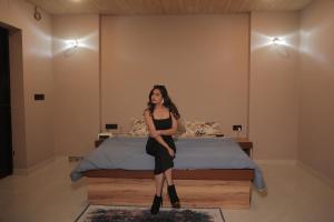 a woman in a black dress sitting on a bed at The triangle haven escape in Ani