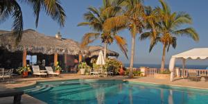 a resort swimming pool with palm trees and the ocean at Villa del Faro in Boca de la Vinorama