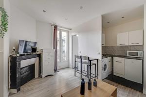 a large kitchen with white cabinets and a table at Cosy Studio - 2P- Clichy in Clichy