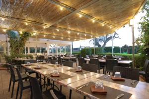 a restaurant with tables and chairs under a wooden pergola at Villa Ghetta Country House in Leverano