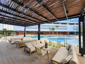 a patio with couches and tables and a pool at Apartamento en Santa Marta frente al mar in Gaira