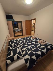 a bedroom with a black and white comforter on a bed at AspenValley Aprtment in Razlog
