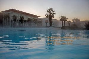 a pool of water with a building and palm trees at HOTEL ZILLNERs EINKEHR *** in Altheim