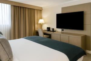 a hotel room with a bed and a desk with a television at Ontario Airport Hotel & Conference Center in Ontario +23 photos