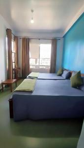 a blue bedroom with two beds and a window at Daya Guest House in Pattipola
