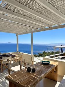 a patio with a wooden table and a view of the ocean at Villa Alisachni Andros in Agia Eleousa +40 photos