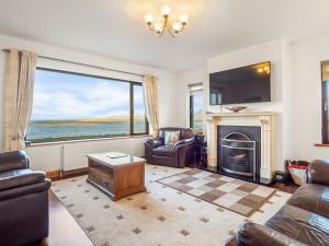 a living room with a fireplace and a large window at Makeelan House in Renvyle