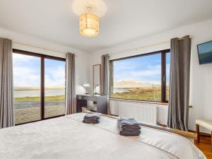 a bedroom with a large bed and large windows at Makeelan House in Renvyle