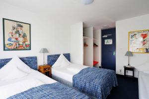 two beds in a room with blue and white at Hotel Nymphenburg City - München in Munich
