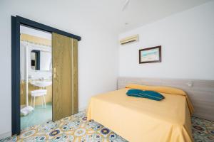 a bedroom with a yellow bed and a mirror at La Residenza Aparthotel in Maiori