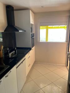 a kitchen with white cabinets and a window at Milles Eclats in Les Anses-dʼArlets