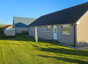 a house with a grass yard next to a house at Inverloch self catering in Orkney