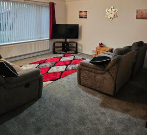 a living room with two couches and a red rug at Inverloch self catering in Orkney