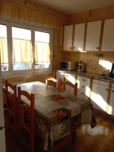 a kitchen with a table and chairs and some windows at Entre els pirineus in La Seu d'Urgell